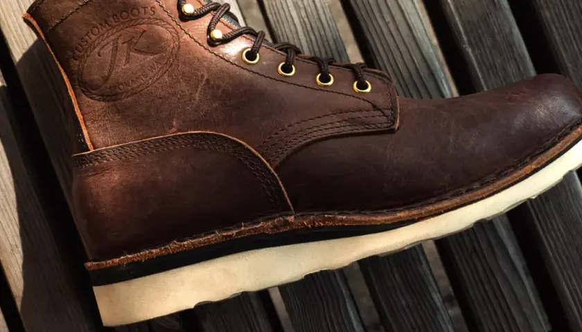 Brown leather boot with white sole. The stitching and laces are visible. This boot might make noise when you walk if the sole is loose.