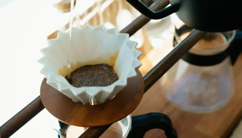 Delikatny strumień wody zaparza kawę po japońsku w papierowym filtrze.