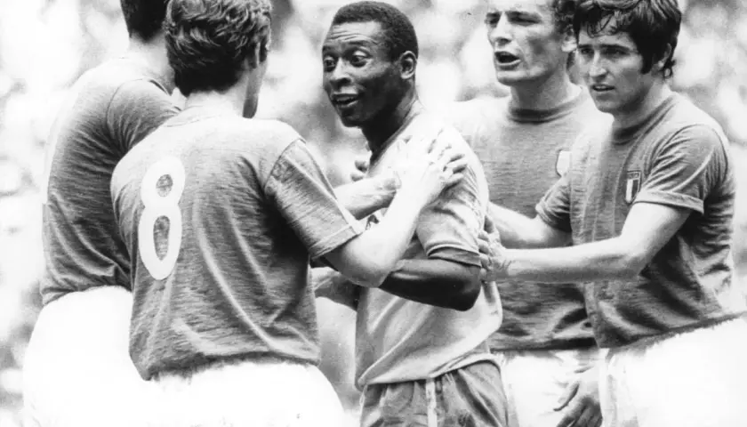 Słynny piłkarz brazylijski, Pelé, otoczony przez innych graczy, w geście sportowego szacunku po meczu.