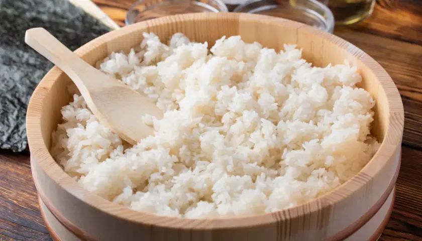 Gotowany ryż do sushi w drewnianej kadzi z drewnianą łopatką.