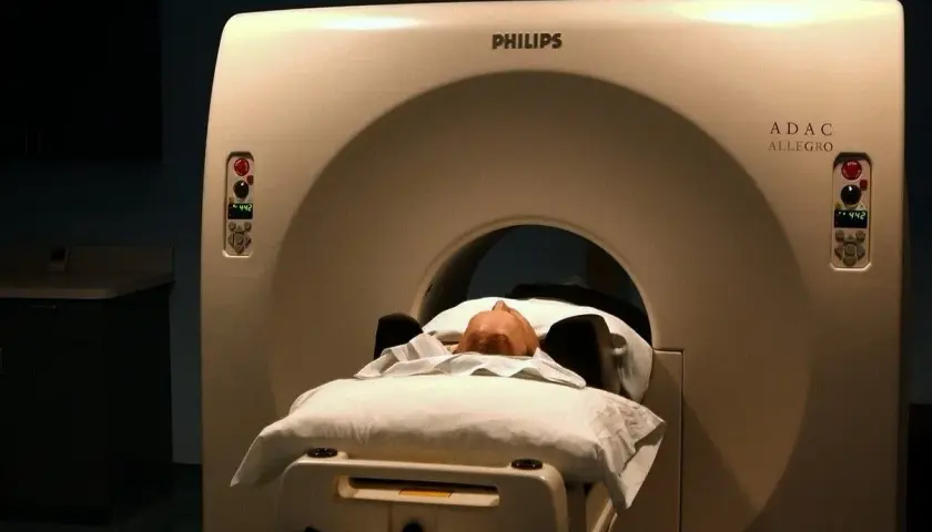 Pacjent leży na łóżku aparatu do tomografii głowy Philips ADAC Allegro.