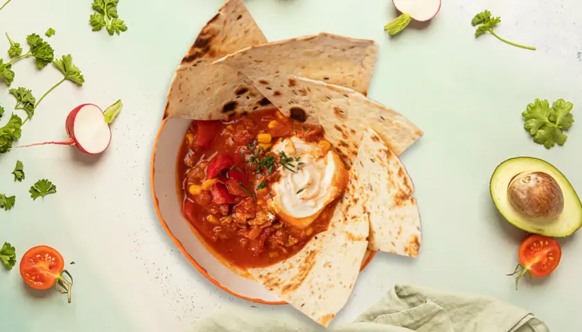 Meksykańska zupa sopa de tortilla z tortillą, śmietaną, kukurydzą i pomidorami.