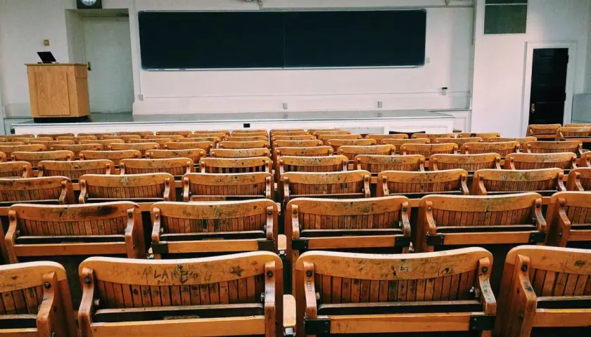 Puste drewniane ławki w sali wykładowej, jakby czekające na studentów w futurystycznym francuskim uniwersytecie.
