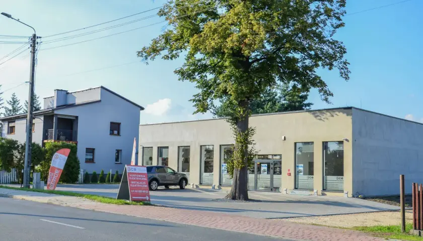 Nowoczesna hurtownia elektryczna w Imielinie. Obok budynku rośnie okazałe drzewo.