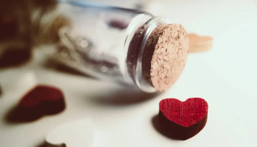 Cuore rosso vicino a una bottiglia tappata, simbolo di innamoramento e amore.