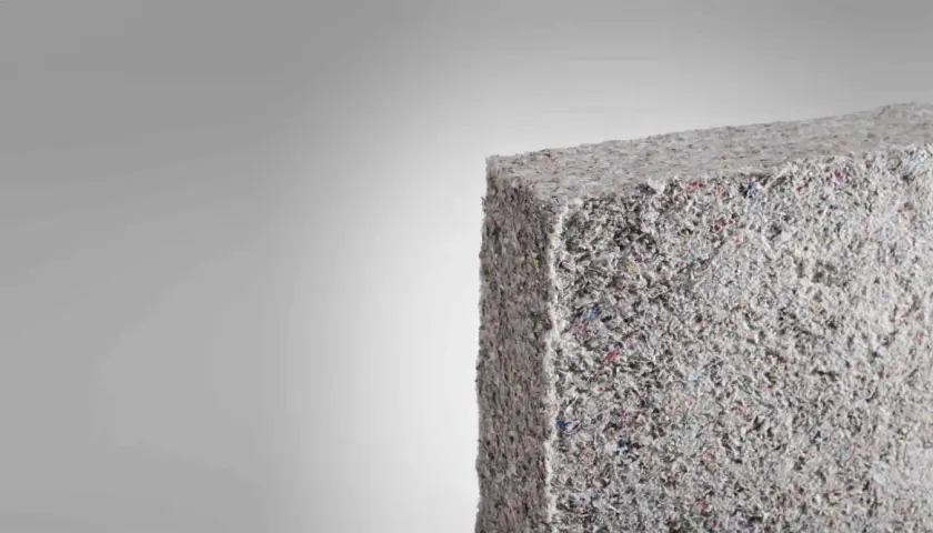 Bloque de material aislante grisáceo, similar a fibra de vidrio triturada. Evitar respirar estas partículas para prevenir consecuencias.