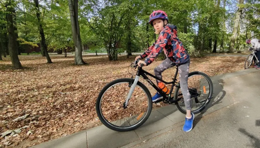 Dziewczynka na rowerze, idealny rower dla 10 latka ile cali? W parku jesienią.