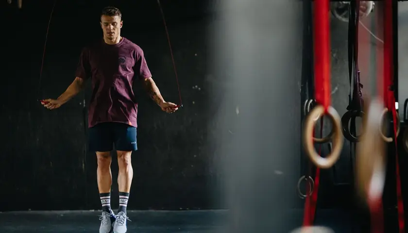 Mężczyzna w sportowym stroju skacze na skakance w siłowni.