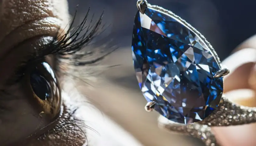 Ein Auge blickt auf einen funkelnden blauen Diamanten, dessen Wert unermesslich ist.