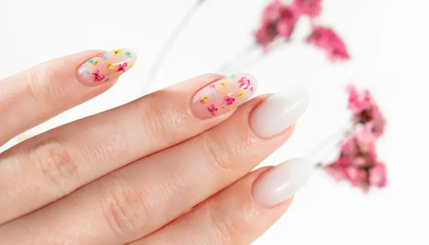 Delikatne, przezroczyste paznokcie z zatopionymi suszonymi kwiatami. Uroczy manicure w wiosennym stylu.