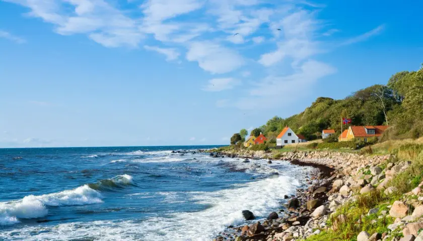 Malownicze domki na wzgórzu, duńska wyspa na Bałtyku, falujące morze i kamienista plaża.