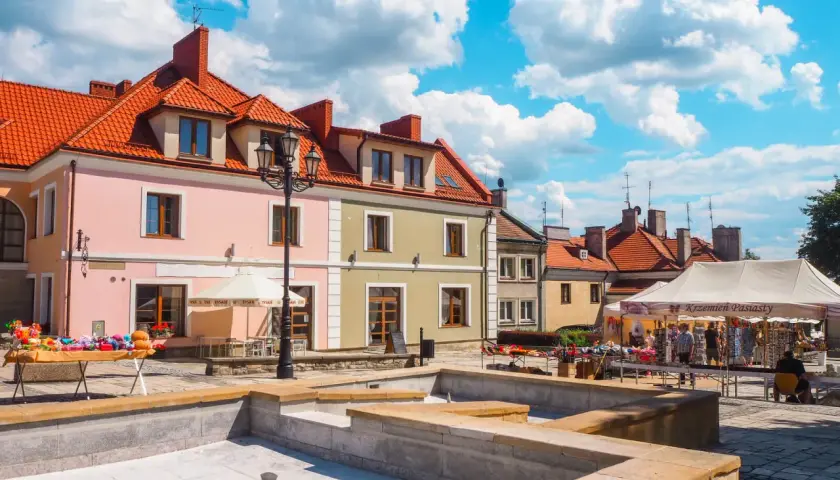 Sandomierz rynek tętni życiem. Kolorowe kamienice, stragany z pamiątkami i błękitne niebo tworzą malowniczy widok.