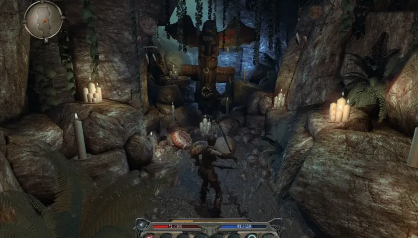 Postać w jaskini z totemicznym posągiem i świecami. Klimat z gry Divinity II: Ego Draconis.