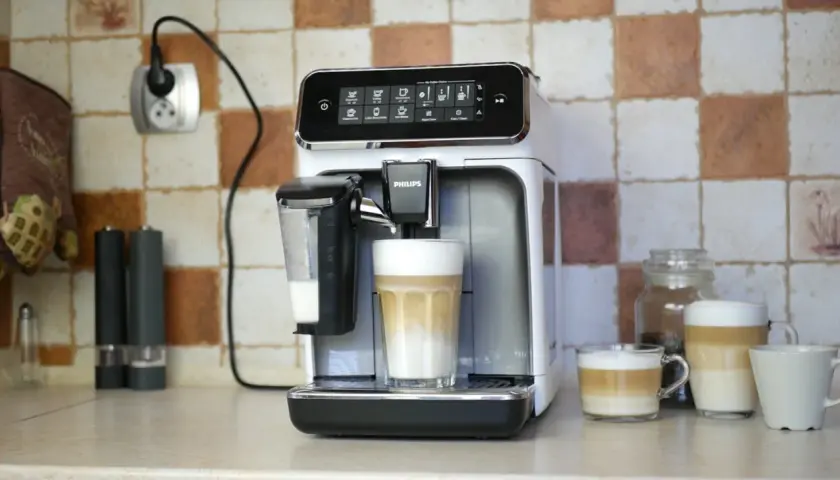 Philips LatteGo 3200 w trakcie czyszczenia obiegu mleka. Na blacie stoi ekspres, obok niego szklanka z kawą latte.