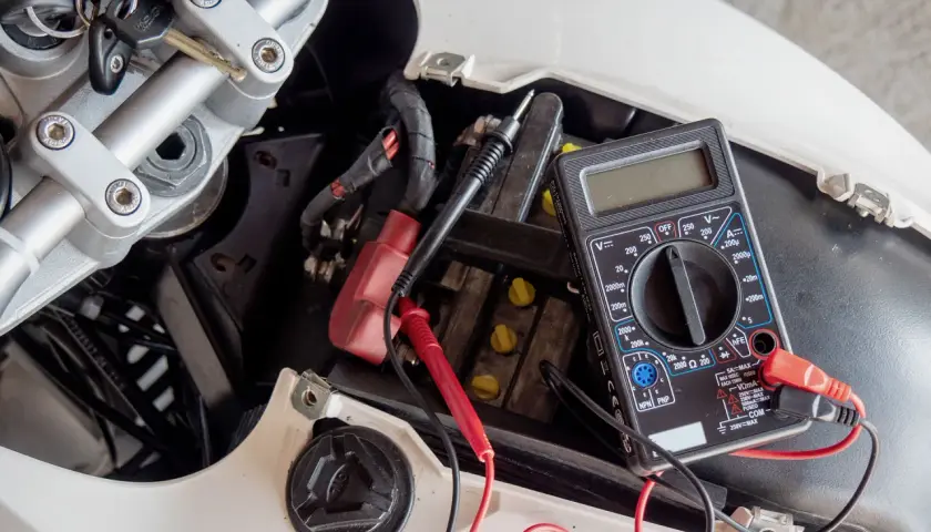 Controllo batteria scooter con multimetro. Si sta per caricare la batteria dello scooter in casa, verificando la tensione con un tester.