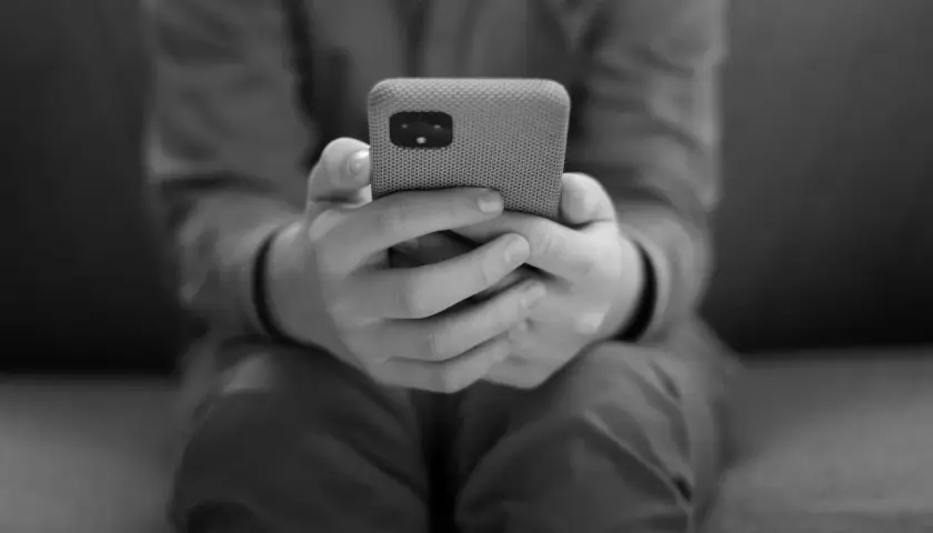 Dłonie trzymające telefon, symbolizujące uzależnienie od telefonu.