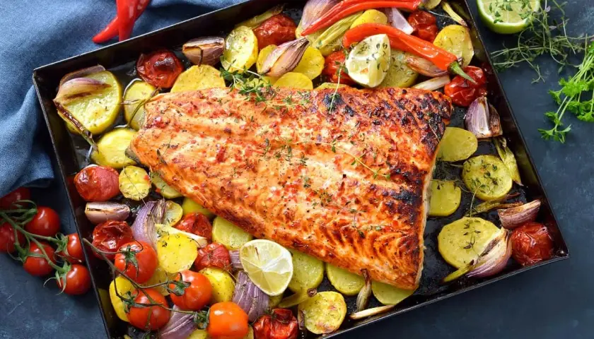 Delicioso pescado al horno con patatas, tomates, cebolla y pimientos. Un plato completo y sabroso.