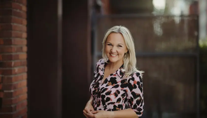 Jenny Fagerlund ler glatt i en mönstrad klänning.