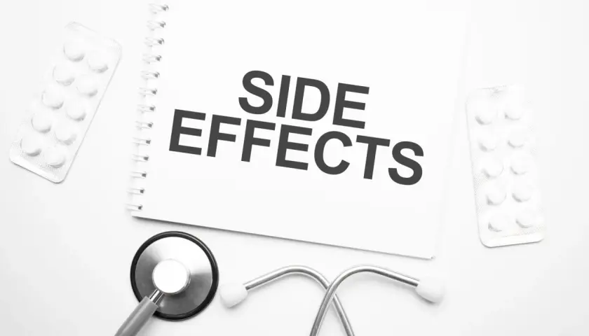 Notatka z napisem "SIDE EFFECTS" obok stetoskopu i blistrów z tabletkami. Czy NAC suplement ma skutki uboczne?