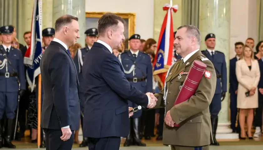 Uroczystość wręczenia nominacji generalskich. W centrum korpus generałów, prezydent Duda wręcza dokument.