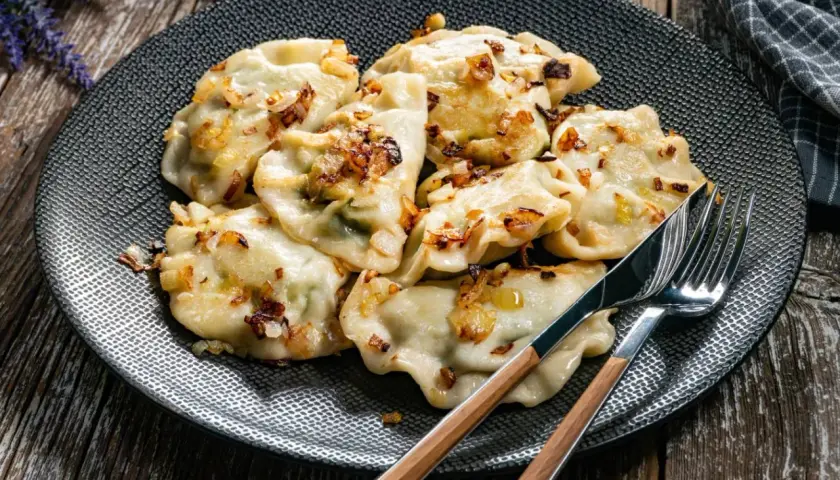 Pyszne pierogi z cebulką na talerzu. Czy rozmrażać pierogi przed gotowaniem? To pytanie zadaje sobie wielu kucharzy.