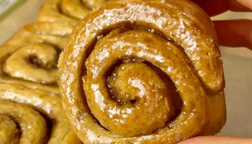 Un primo piano di soffici cinnamon rolls glassati, con la loro spirale invitante e il profumo di cannella che sembra quasi percepibile.