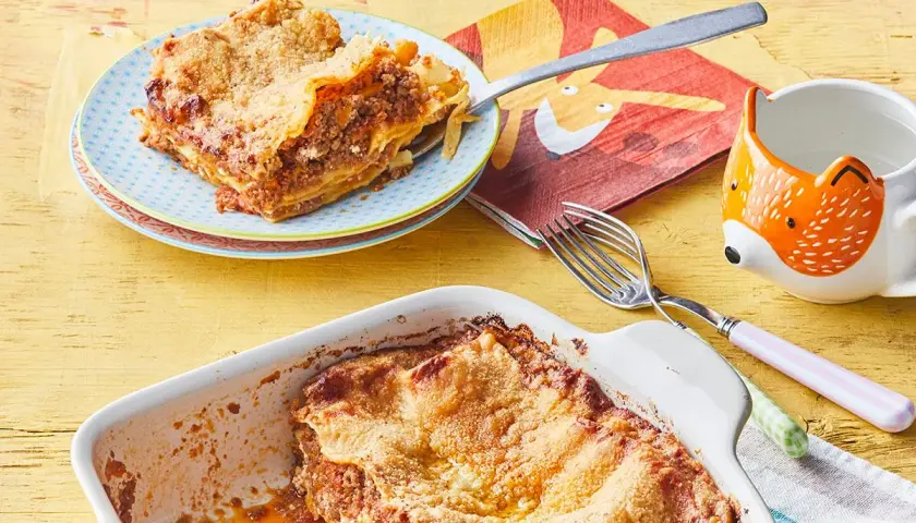 Lasagne maison : une part de recette lasagne ricotta viande hachée sur une assiette, le plat encore plein à côté.