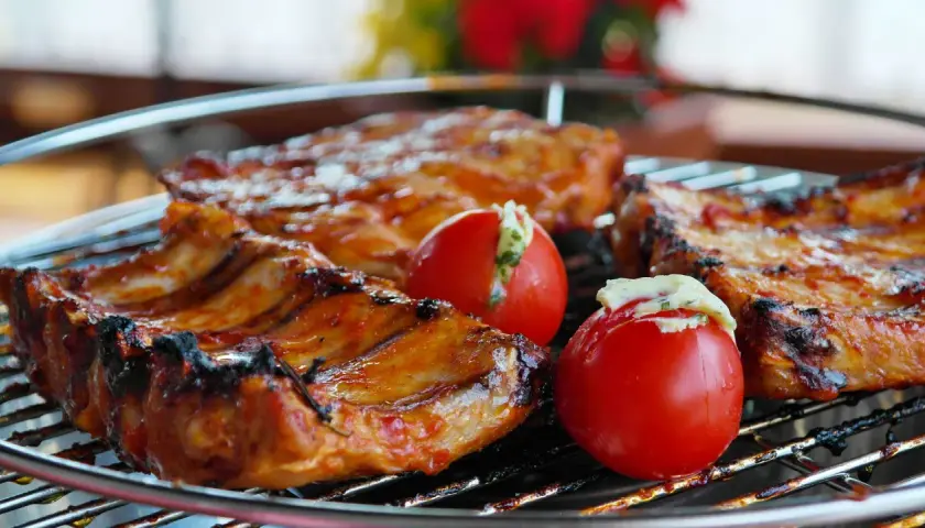 Côtelettes de porc grillées, savourant la qualité de la viande espagnole, accompagnées de tomates farcies.