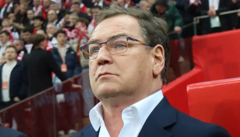 Trener w okularach z uwagą obserwuje trybuny, być może analizując potencjalnych kandydatów do reprezentacji.