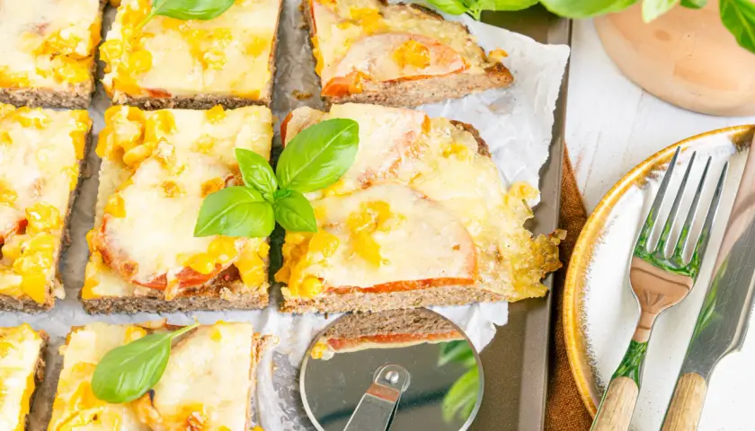 Herzhafte hackfleischpizza vom blech, Landfrauen-Art, mit Tomaten und Käse überbacken, garniert mit frischem Basilikum.