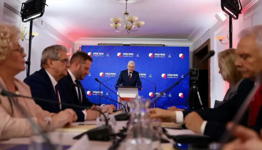 Ludzie siedzą przy stole, słuchając przemówienia. To pokazuje, co można robić po prawie – brać udział w debatach i konferencjach.