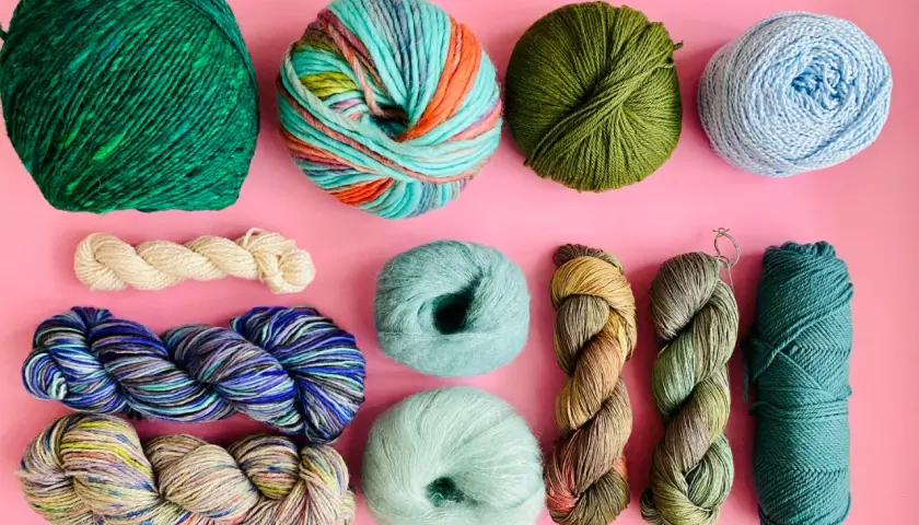 Assortiment de pelotes de laine aux couleurs vives et naturelles, évoquant l'origine de la laine et la beauté de la nature.