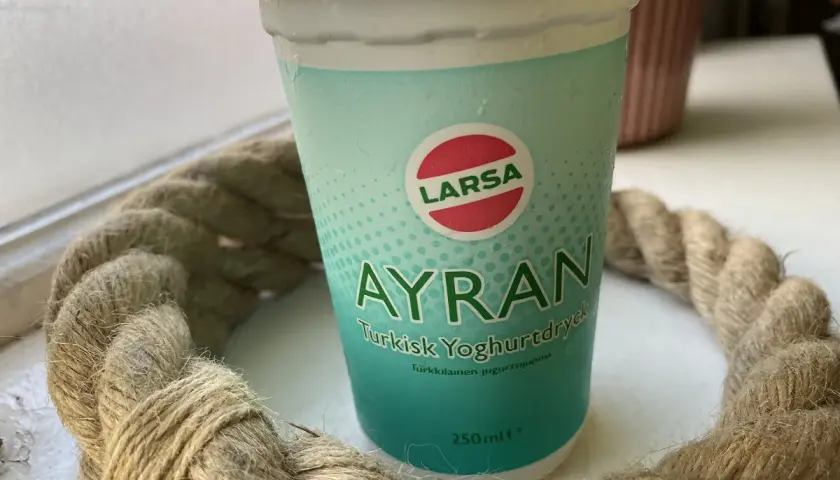 En kopp Larsa Ayran, turkisk yoghurt, står på ett bord. Perfekt för ett snabbt ayran recept.