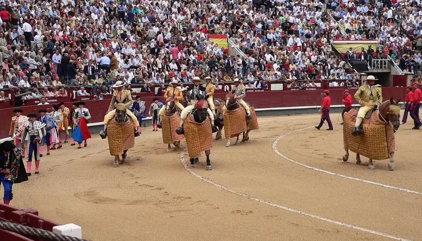 Inicio de que es una corrida de toros: picadores a caballo con caparazones, toreros y público en las gradas.