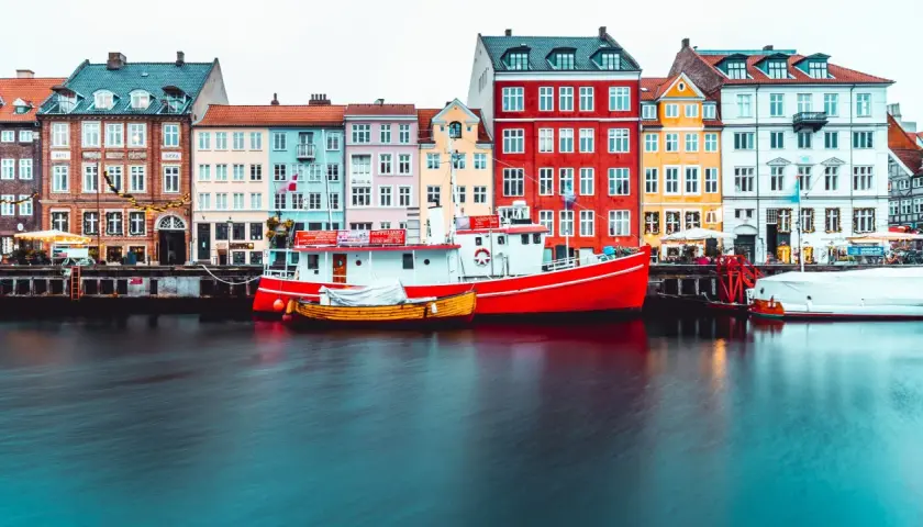 Bateaux rouges et jaunes amarrés devant des maisons colorées, typiques de Copenhague.