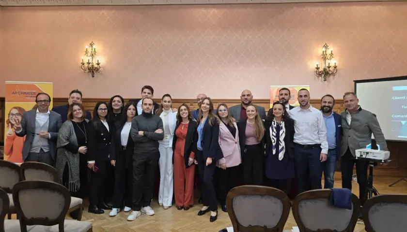 Gruppo di persone posa davanti a uno striscione della Fondazione Archimede.