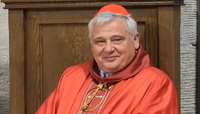 Uśmiechnięty kardynał w czerwonej sutannie i piusce. Kto jest nad biskupem? To on, w swojej uroczystej szacie.