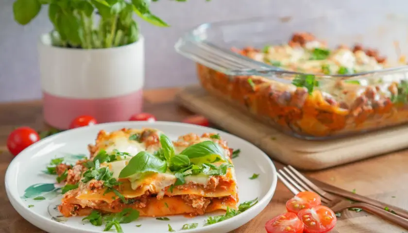 Pyszna lasagne na talerzu, z bazylią i pomidorkami. Idealnie, gdy zastanawiasz się, co podać do lasagne.