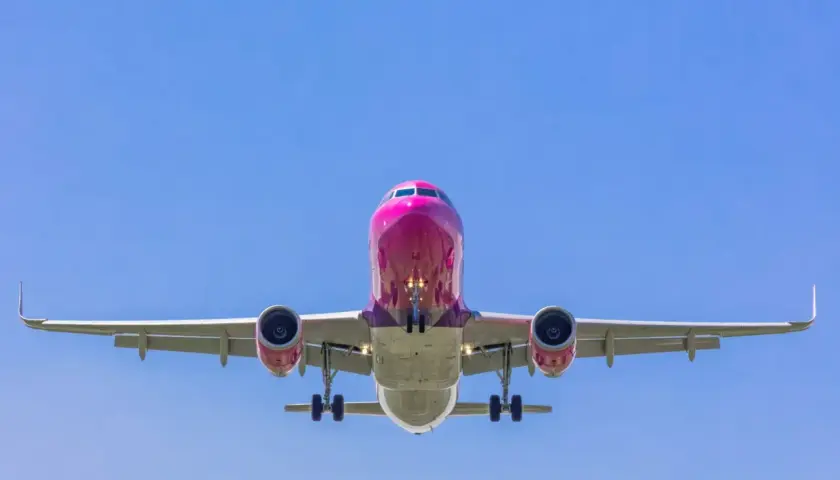 Różowy samolot Wizzair z wysuniętym podwoziem, gotowy do lądowania. Tak wygląda odprawa online Wizzair - szybko i sprawnie!