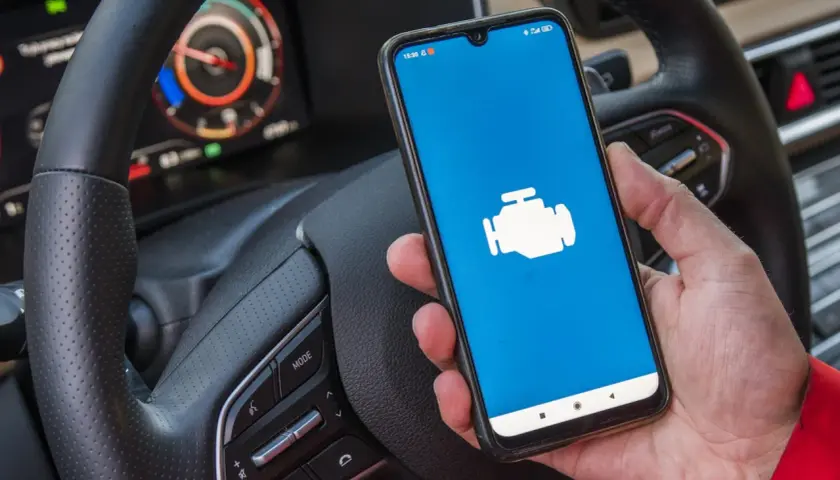 Dacia Sandero z ikoną silnika na ekranie telefonu, gotowa do diagnostyki OBD.
