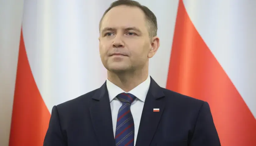 Mężczyzna w garniturze przed polską flagą. Czy to symbol ukrytych kosztów utrzymania Kancelarii Prezydenta RP w ostatnim roku kadencji?