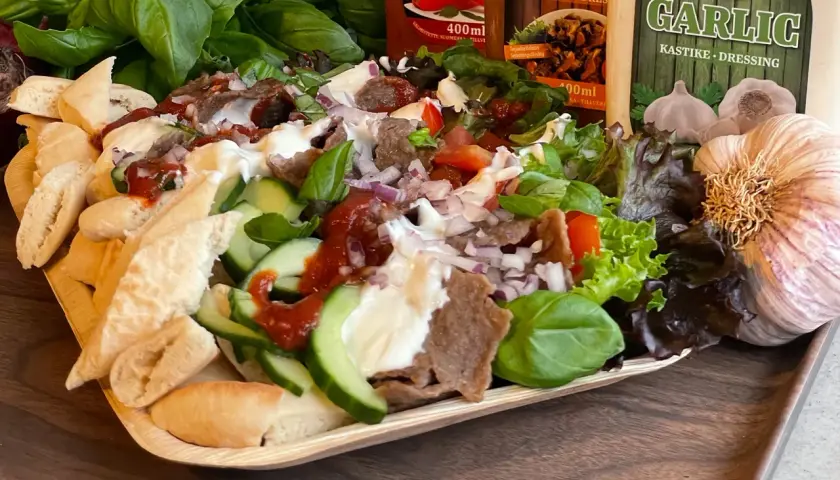En läcker tallrik med iskender kebab, fylld med kött, grönsaker, bröd och såser. Perfekt för en smakrik måltid.
