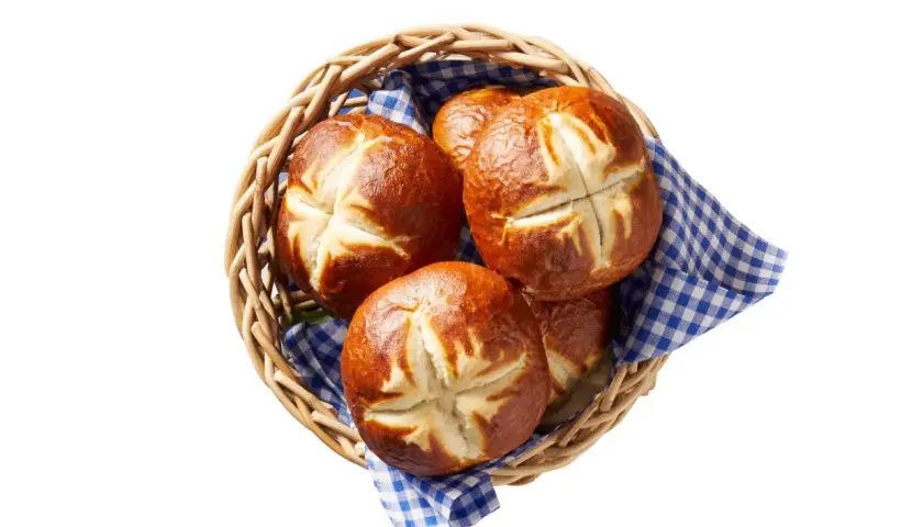 Koszyk z chrupiącymi bułkami bawarskimi, ozdobiony niebiesko-białą kratką. Idealne na śniadanie.