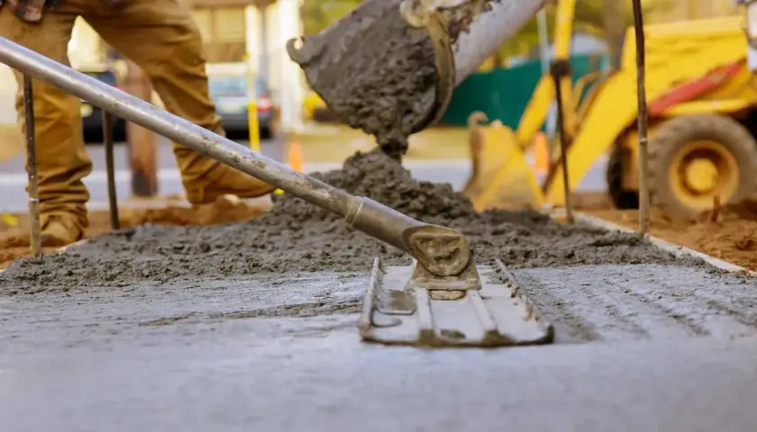 Wylewanie i wyrównywanie świeżego betonu na budowie.