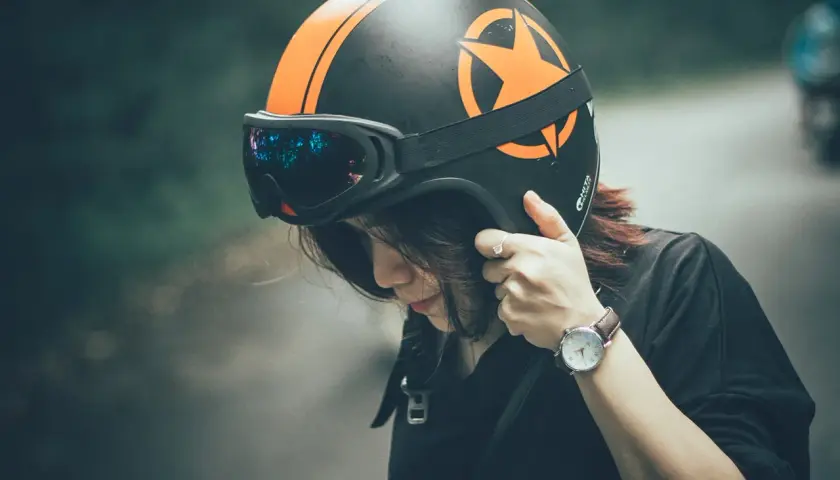 Ragazza con casco moto nero e arancione, occhiali riflettenti. Guida sicura: ecco come scegliere casco moto.