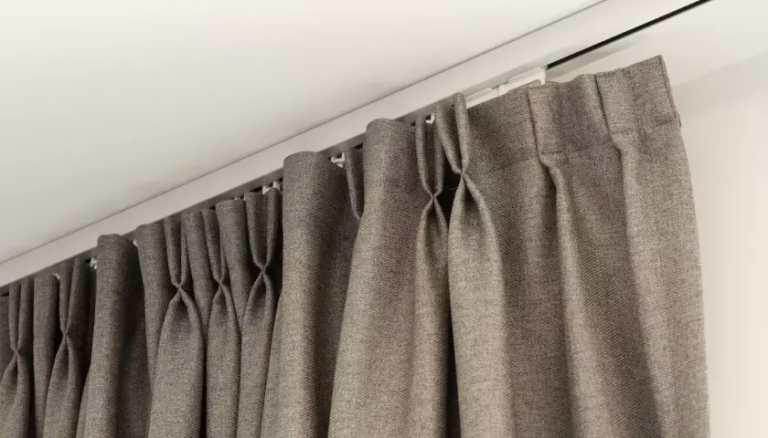 Szare zasłony wiszą na podwójnym karniszu elektrycznym, tworząc elegancką aranżację okna.