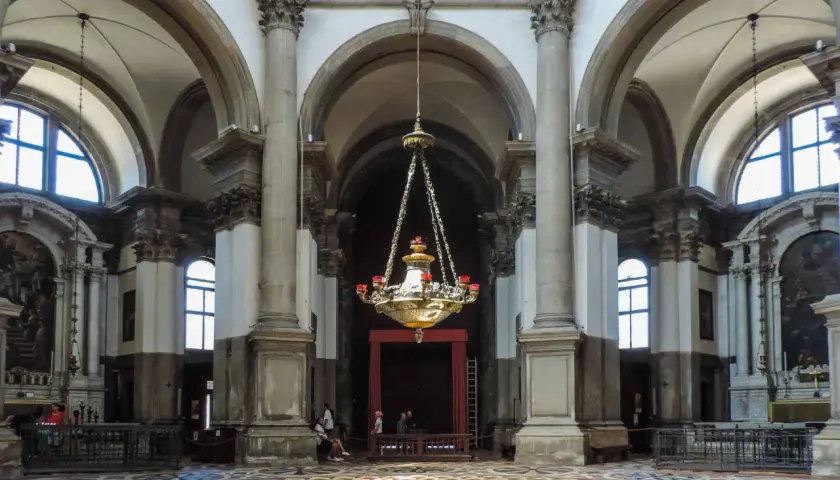 Intérieur de la basilique Santa Maria della Salute, avec son lustre imposant, ses colonnes majestueuses et son sol orné.