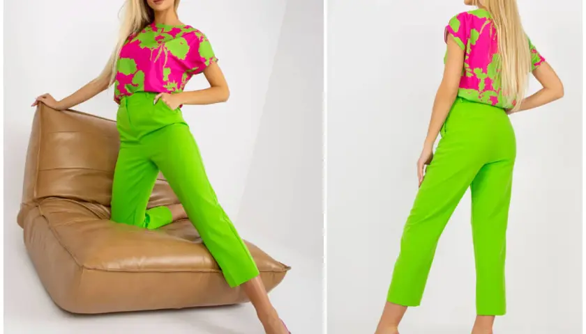 Modelka w stylizacji z bluzką w intensywny wzór i spodniami w kolorze limonkowym, siedząca na brązowej poduszce.