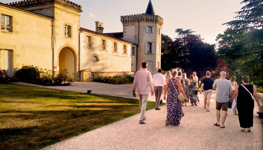 Un groupe de personnes se promène sur le chemin menant au **château Toulouse Lautrec** au coucher du soleil.