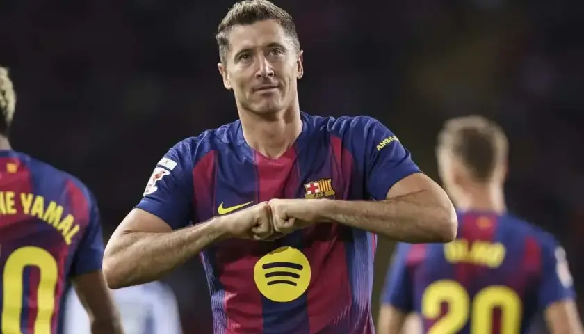 Robert Lewandowski w koszulce Barcelony, z gestem radości. Zastanawiasz się, ile zarabia Lewandowski na minutę?